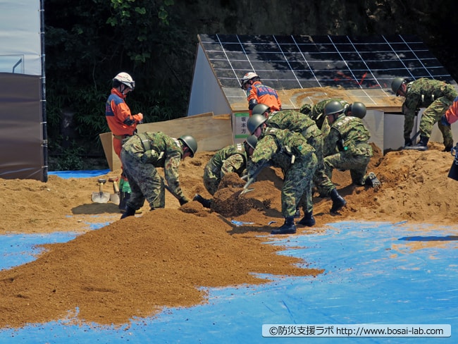 陸上自衛隊第3特科隊がバケツリレー方式で、埋もれた家屋の土砂を素早く排出。