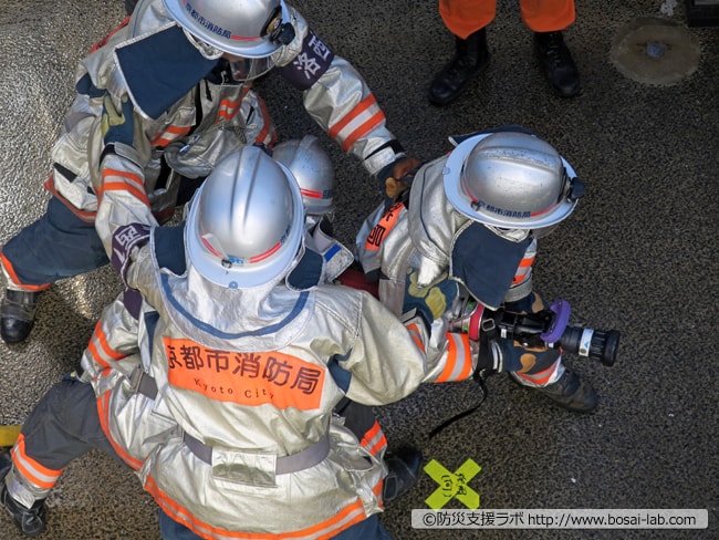 特別高度工作車の前へ立ち放水の準備へ。京都の消防士の活動写真。