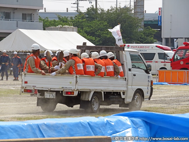 岸和田市の多数の水防団員がトラックの荷台へ10人ずつ乗り込んで訓練会場へ入場。