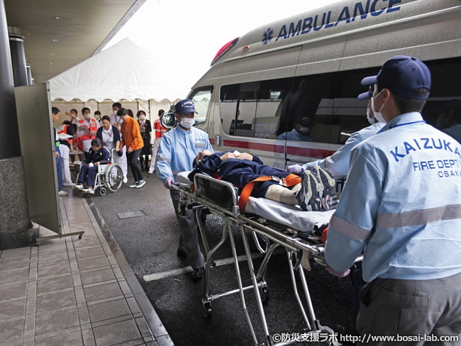 貝塚市消防本部の協力で傷病者の受入がスタート。搬送されてくる傷病者役は看護学校の学生が多数参加しました。